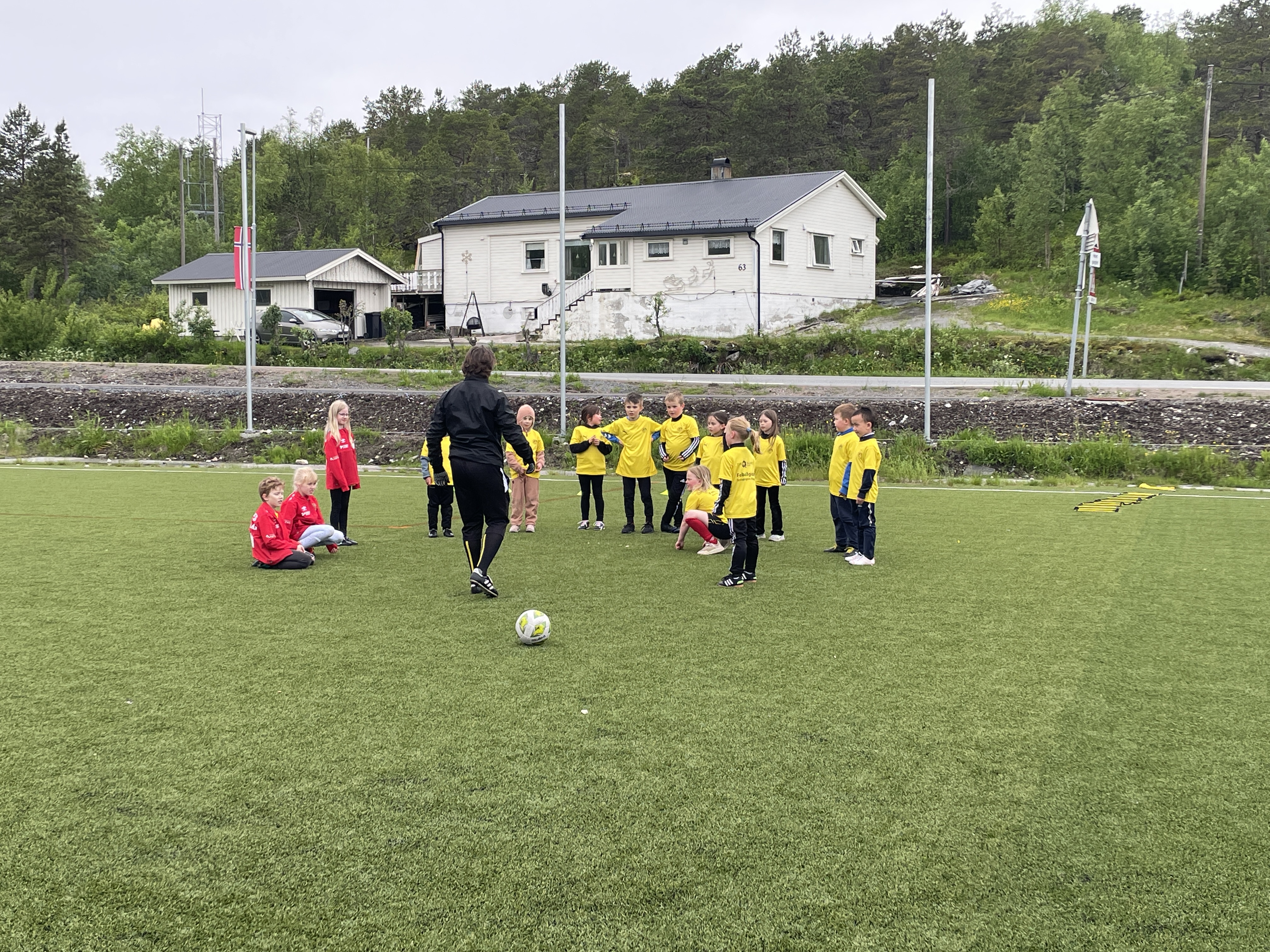Barn samlet rundt treneren på fotballbanen
